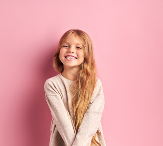 Portrait of happy, smiling girl against pink background