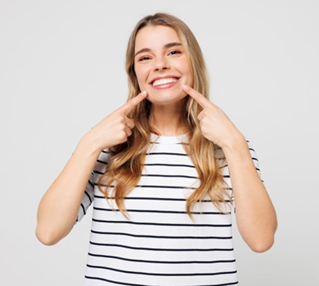 Woman pointing at her smile after orthodontic treatment