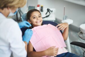 Happy young girl smiling in dental chair