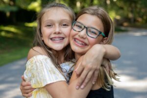 Two young girls with braces hugging
